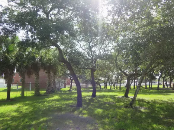 Fenced-off lighthouse with historical buildings.