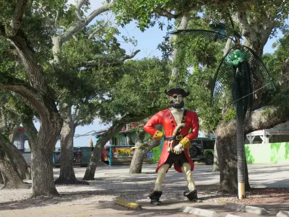 Fenced-off lighthouse with historical buildings.