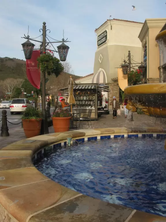 Fountain, stores, and hills behind.