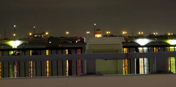 Wide walking path along the water with tropical flowers, piers, grand high rises, and palm trees- no shade though.