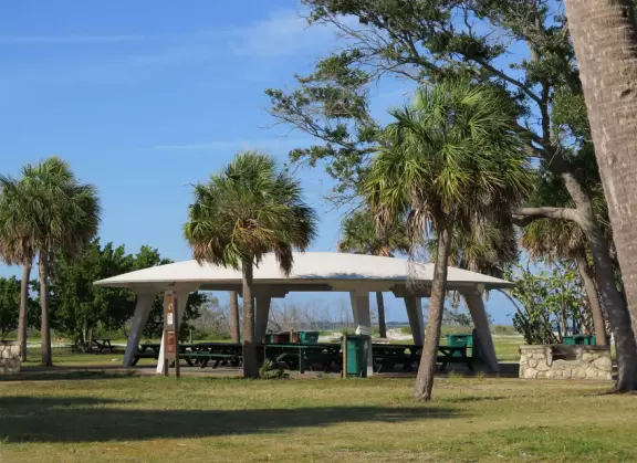 White sand beach with dunes and murky lagoon.