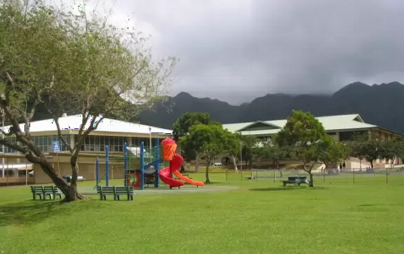 A beautiful park with playground, fields, trees and mountains all around.
