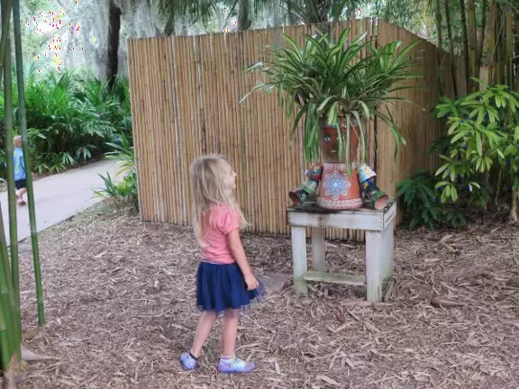 A girl delights in a funny little guy made of pots.