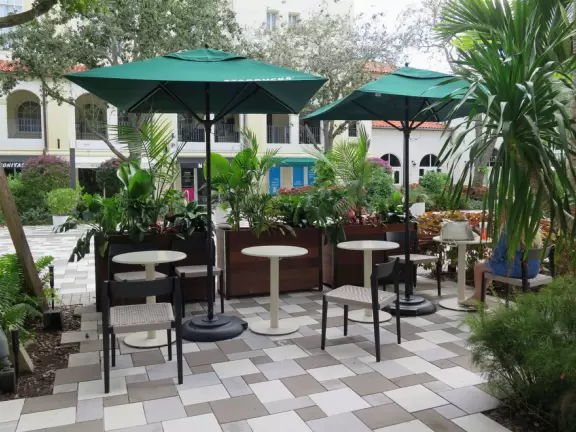 Outdoor shopping and entertainment district with European architecture, archways, palms, tropical flowers, and amazing fountain for kids.