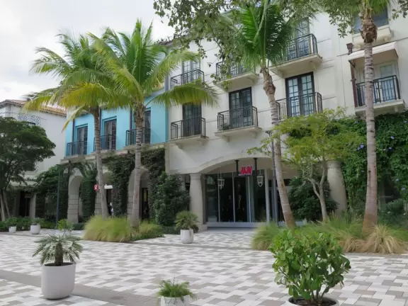 Outdoor shopping and entertainment district with European architecture, archways, palms, tropical flowers, and amazing fountain for kids.