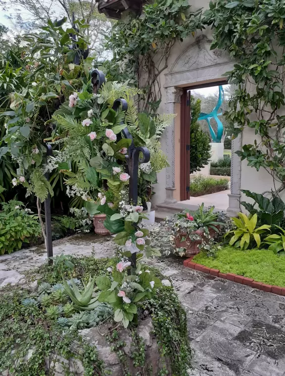 A tropical wonderland of palms, ferns, bromeliads, fountains, sculptures, rocks, ironwork gates, and pergolas, with the delightful scent of flowers filling the air.