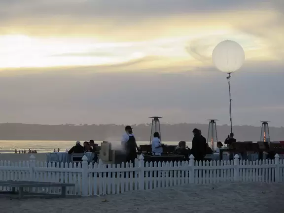 Historic resort with red turrets on foggy beach of fine white sand.