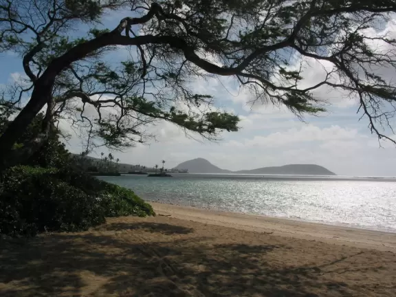 Corally beach with gorgeous views of Koko Head, Koko Crater, and Kahala Resort; plus an expansive lawn and bridge over a stream.