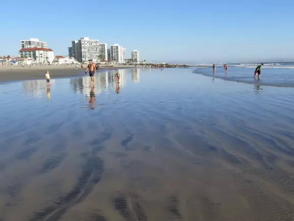 Historic resort with red turrets on foggy beach of fine white sand.