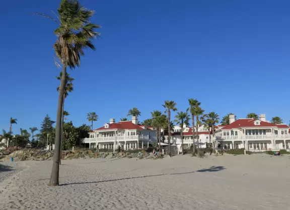 Historic resort with red turrets on foggy beach of fine white sand.