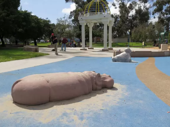 Large playground with animals to climb on, and beautiful trees.