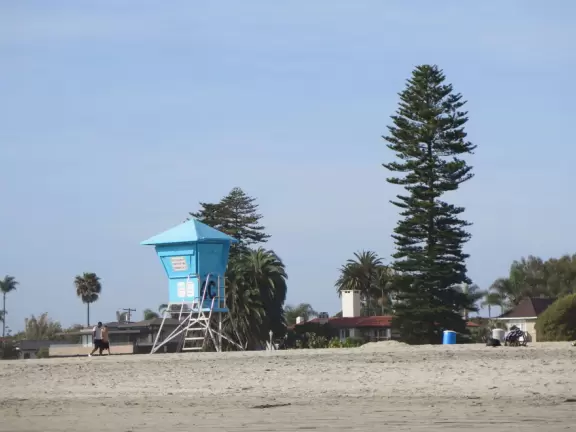 Historic resort with red turrets on foggy beach of fine white sand.
