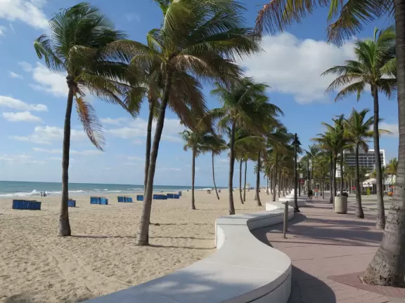 Thin strip of beach with shadeless boardwalk, white swirly wave wall, nice sand, unattractive people, and had-better-days condos.