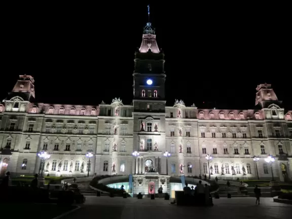 Impressive, stately building atop a hill, with lovely gardens and statues, and a fountain in the middle if the street.