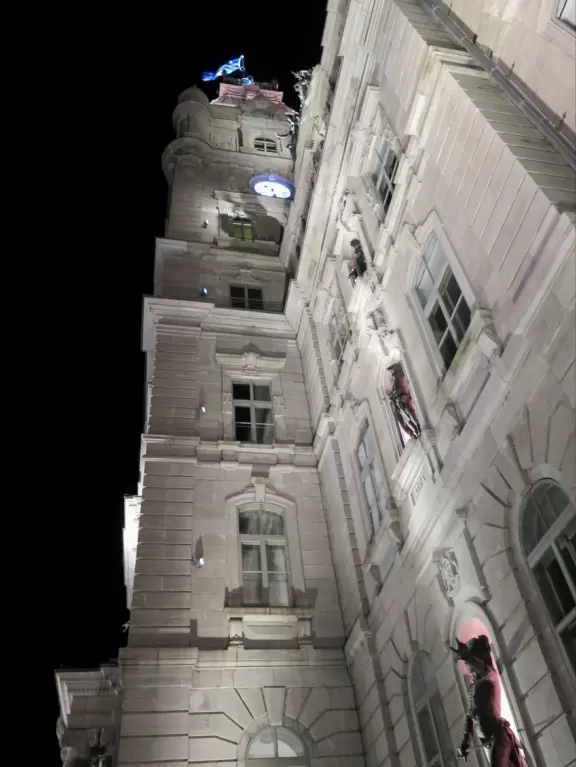 Impressive, stately building atop a hill, with lovely gardens and statues, and a fountain in the middle if the street.