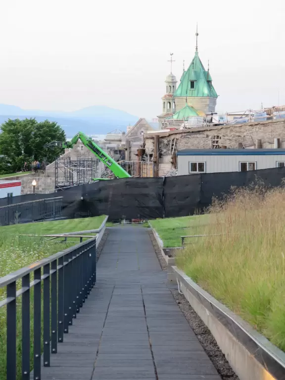 Impressive, stately building atop a hill, with lovely gardens and statues, and a fountain in the middle if the street.