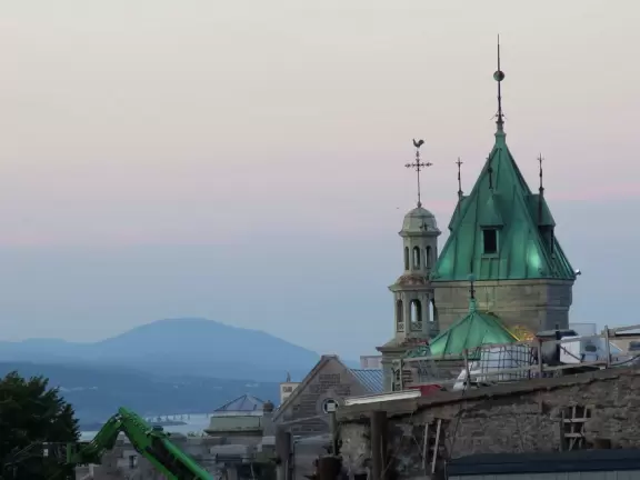 Impressive, stately building atop a hill, with lovely gardens and statues, and a fountain in the middle if the street.