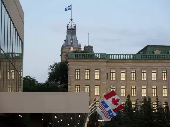 Impressive, stately building atop a hill, with lovely gardens and statues, and a fountain in the middle if the street.