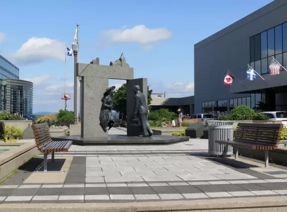 Impressive, stately building atop a hill, with lovely gardens and statues, and a fountain in the middle if the street.