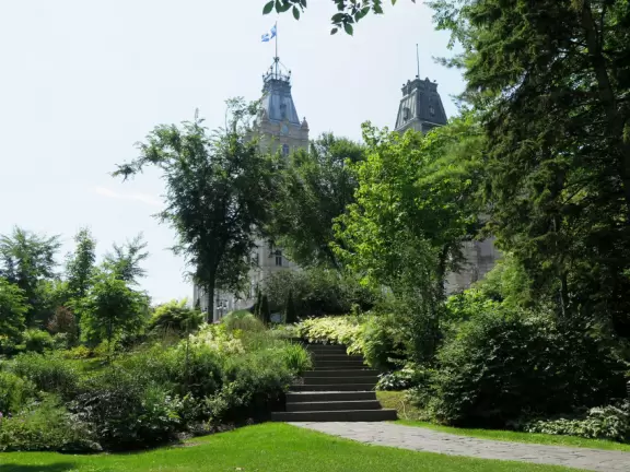 Impressive, stately building atop a hill, with lovely gardens and statues, and a fountain in the middle if the street.