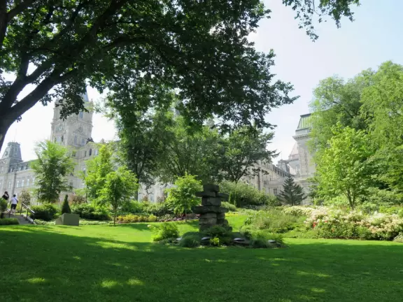 Impressive, stately building atop a hill, with lovely gardens and statues, and a fountain in the middle if the street.