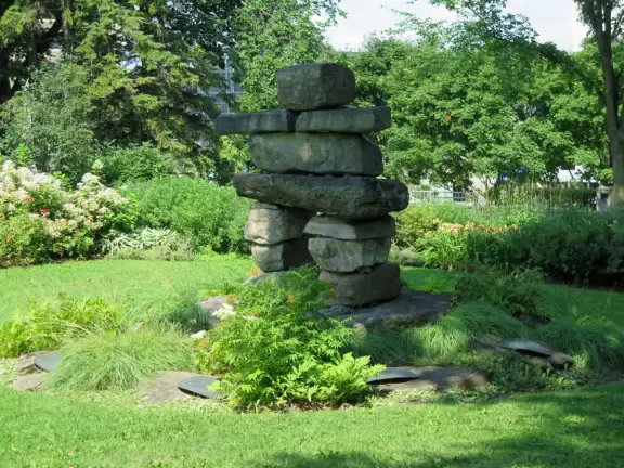 Impressive, stately building atop a hill, with lovely gardens and statues, and a fountain in the middle if the street.