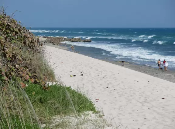 People gather at the walkway above the beach to watch the sunset.