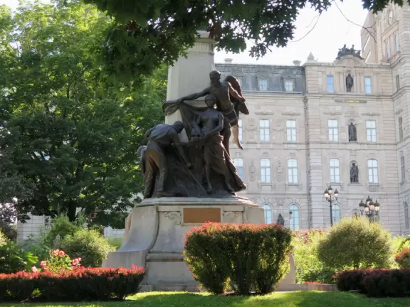 Impressive, stately building atop a hill, with lovely gardens and statues, and a fountain in the middle if the street.