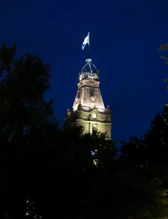 Impressive, stately building atop a hill, with lovely gardens and statues, and a fountain in the middle if the street.