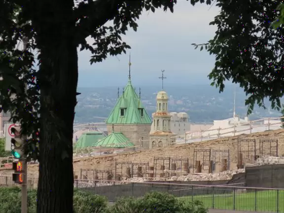 Impressive, stately building atop a hill, with lovely gardens and statues, and a fountain in the middle if the street.