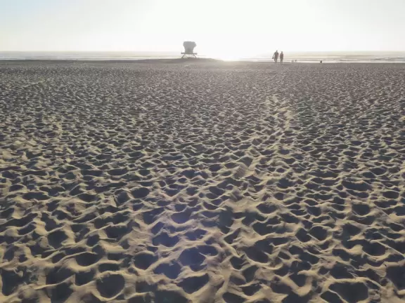 A glorious beach in Grover Beach town, with sand dunes and a wooden boardwalk, plus an octagon-shaped wooden pier in the sand.