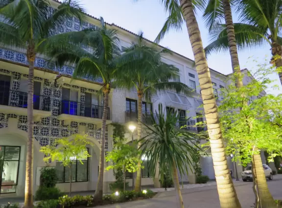 Outdoor shopping and entertainment district with European architecture, archways, palms, tropical flowers, and amazing fountain for kids.