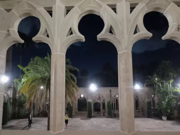 Delightful garden behind a gothic church, with lily pond, koi fish, tropical flowers, sculpted coral walls, fountain, and fresco.