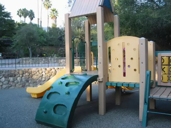A green sloped lawn with huge, healthy pines that shade you, picnic areas with hanging vines, and a toddler playground.