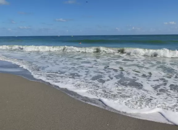Lovely beach with thin ribbon of sand backed by high walls of dunes, and across the street, a playground with white sand and swings.