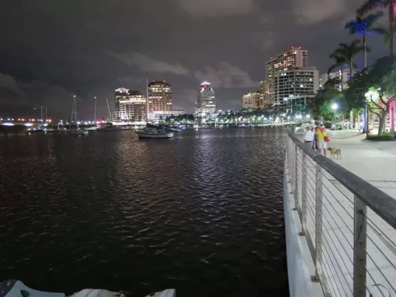 Wide walking path along the water with tropical flowers, piers, grand high rises, and palm trees- no shade though.