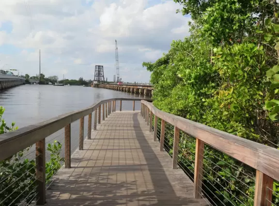 Waterfront park with walking paths under a zillion coconut trees, ship playground in white sand, hopscotch, and colorful pictures and hopscotch on the path.