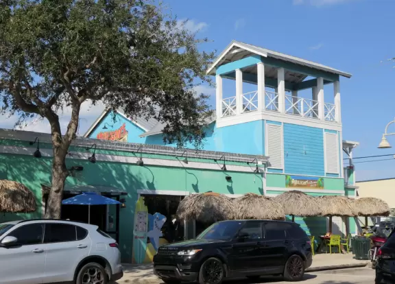 Main block with tropical-themed cafes and views of the water, plus a coffee shop and gift shops in little houses.