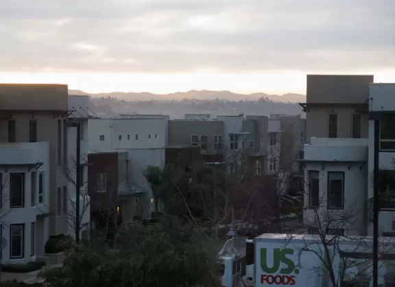 Street with shops and tiny coffee shop, and city views behind.