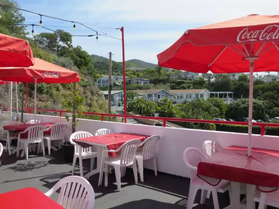 Sit on their rooftop patio under red umbrellas checking out the sea and the hills covered in tropical plants. Check out their 1950s cars and decor!
