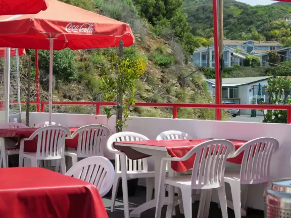 Sit on their rooftop patio under red umbrellas checking out the sea and the hills covered in tropical plants. Check out their 1950s cars and decor!