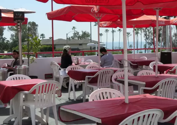 Sit on their rooftop patio under red umbrellas checking out the sea and the hills covered in tropical plants. Check out their 1950s cars and decor!