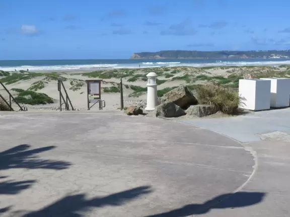 Historic resort with red turrets on foggy beach of fine white sand.