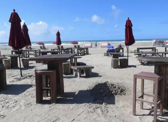 Historic resort with red turrets on foggy beach of fine white sand.