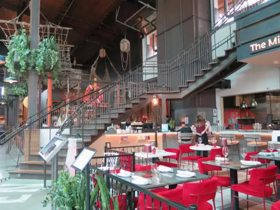 Shopping plaza with a deck offering lots of attractive public space, a trampoline for young kids, a sky deck bar, a dark public market with lights, cafes, stores and coffee shops.