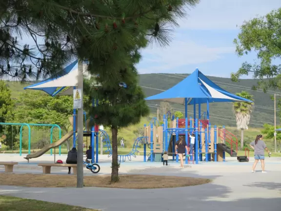 Large field with sweeping views, playgrounds, workout stations, picnic pavilions, and walking path around the field.