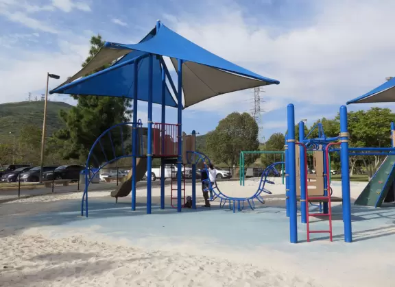 Large field with sweeping views, playgrounds, workout stations, picnic pavilions, and walking path around the field.