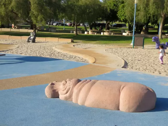 Large playground with animals to climb on, and beautiful trees.