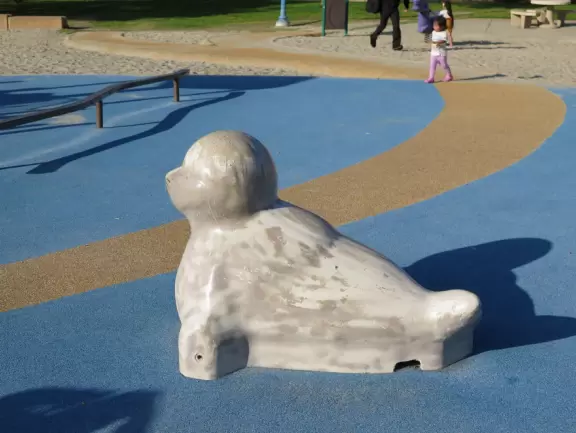 Large playground with animals to climb on, and beautiful trees.