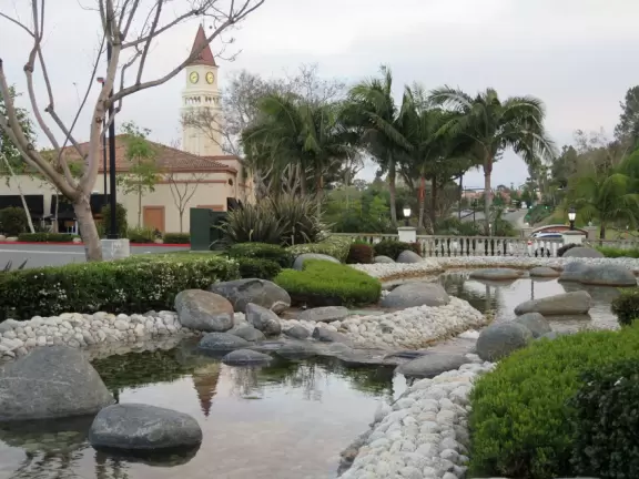 Small shopping plaza with pretty clock tower and landscaped stream.